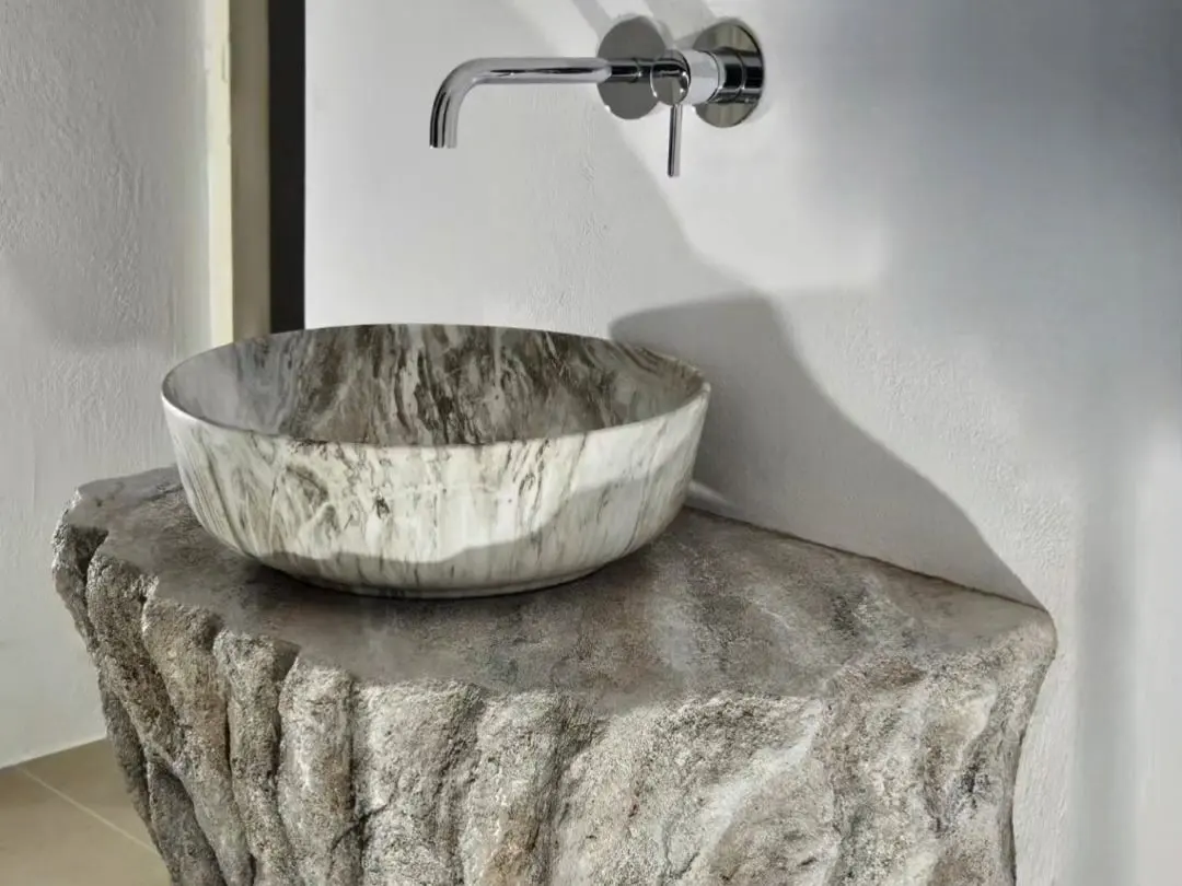 A carved stone basin resting on a hand-shaped stone pedestal