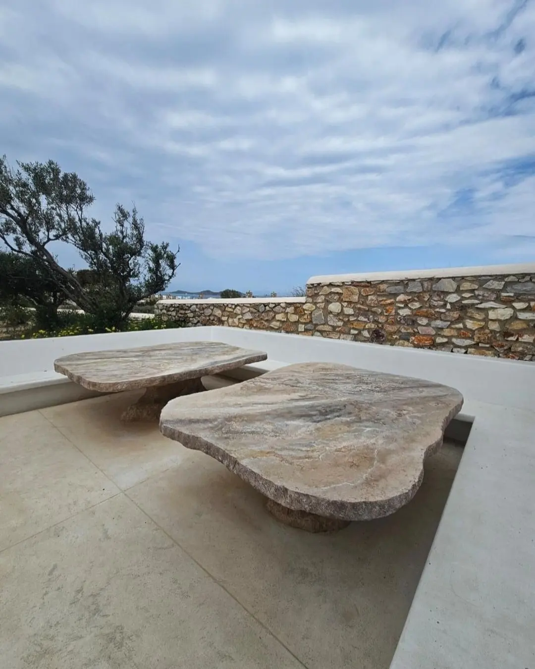 Two sculptural stone tables on the terrace, the sea wall behind them