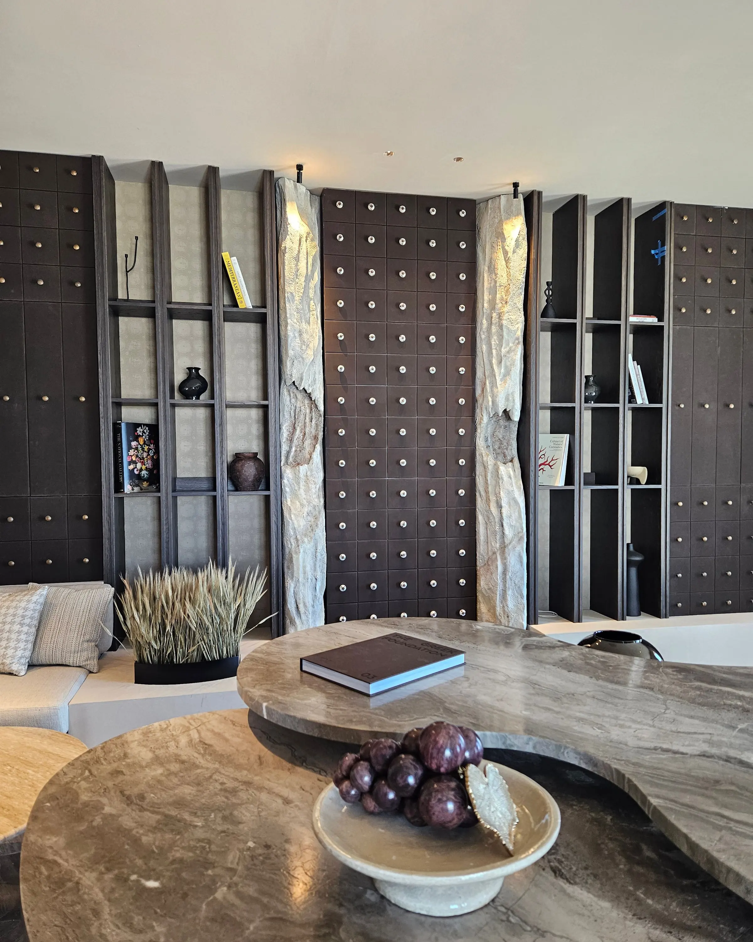 The polished stone counter closer in, with sculpted stone columns framing the shelving behind it