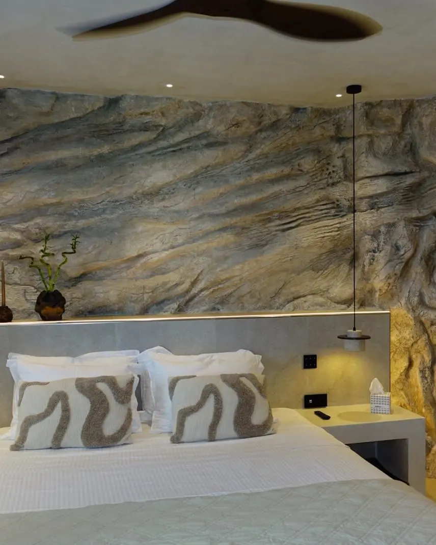 The finished room seen from the foot of the bed, the rock wall running its full width