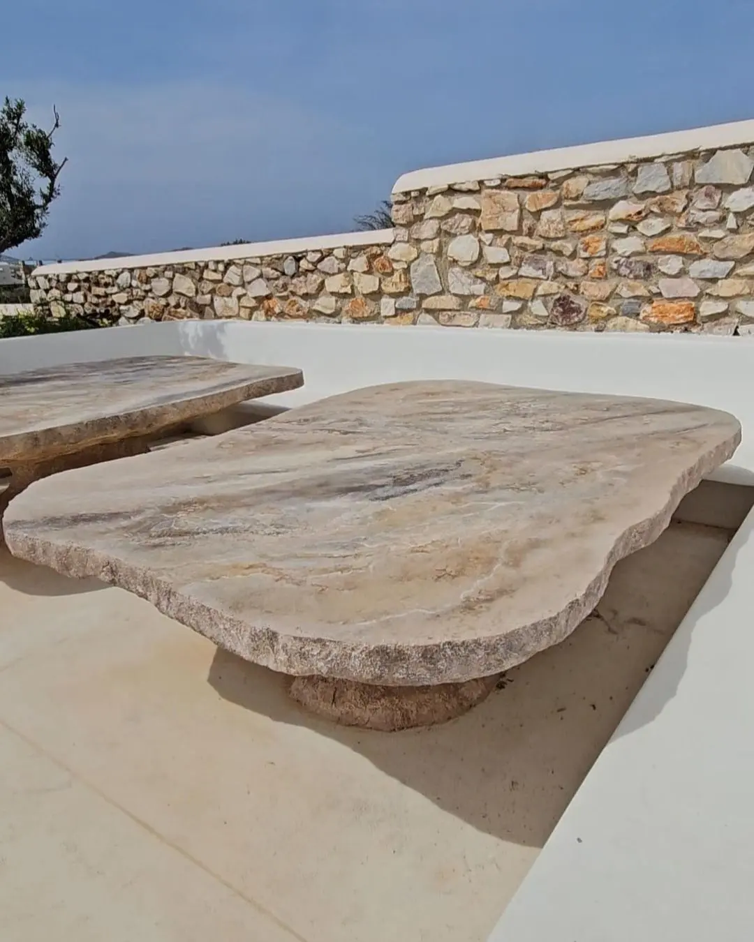 The stone tables in front of a traditional Cycladic dry-stone wall