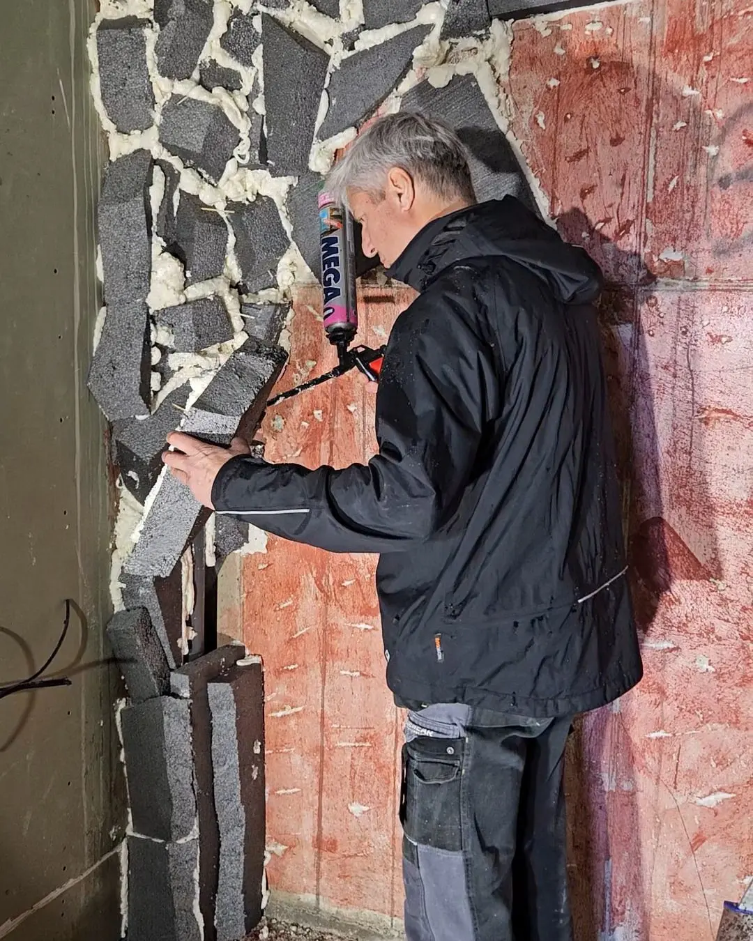 Setting stone pieces into the mesh armature of a wall, before the surface is sculpted over it