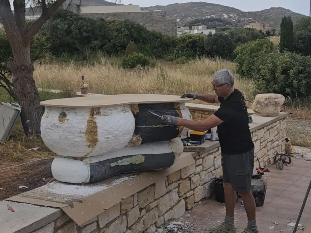 Shaping and finishing the stone base of the piece outdoors on site